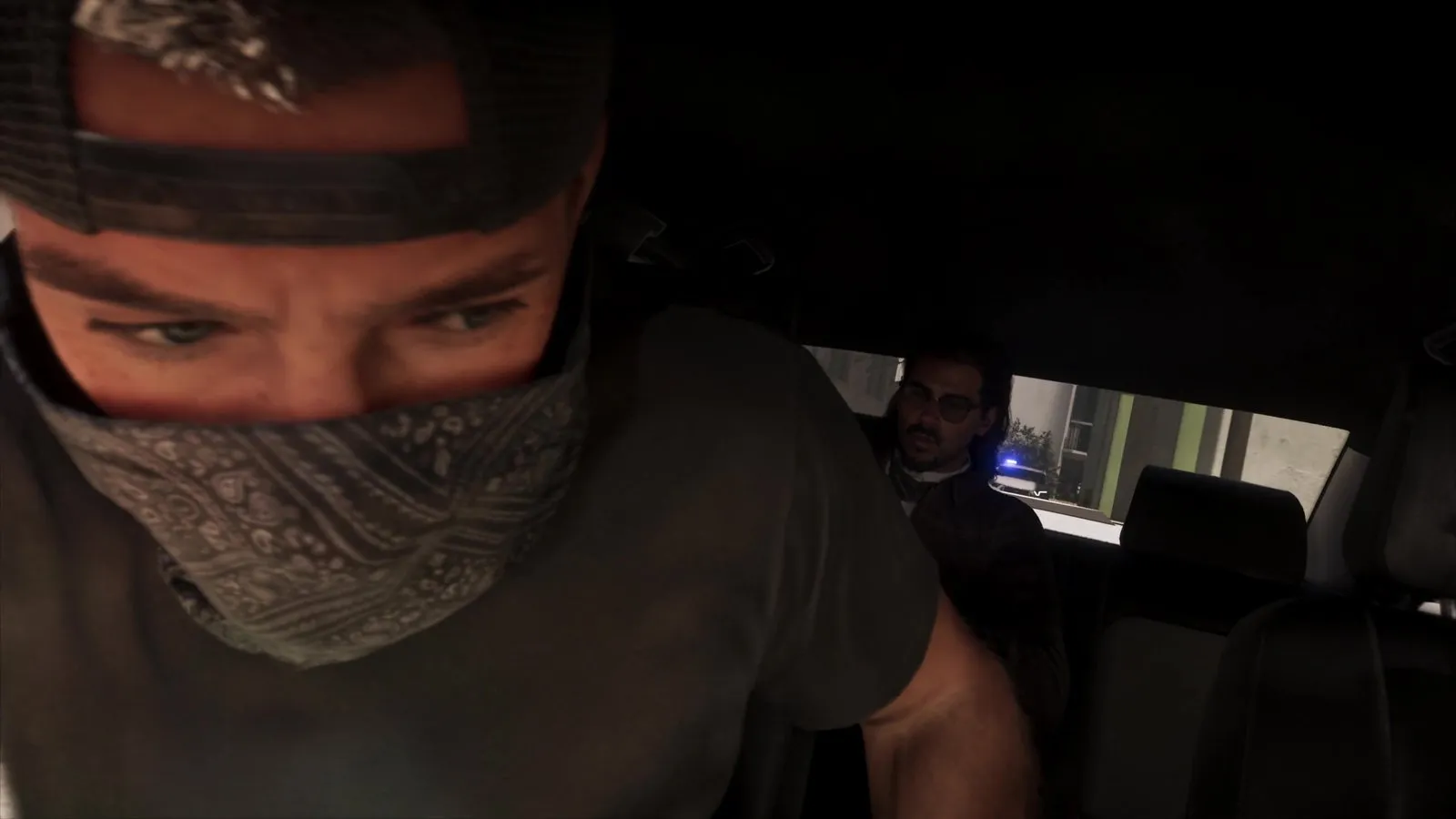A masked man and a back seat passenger sit in a car while a white police car with blue lights on is visible behind them.
