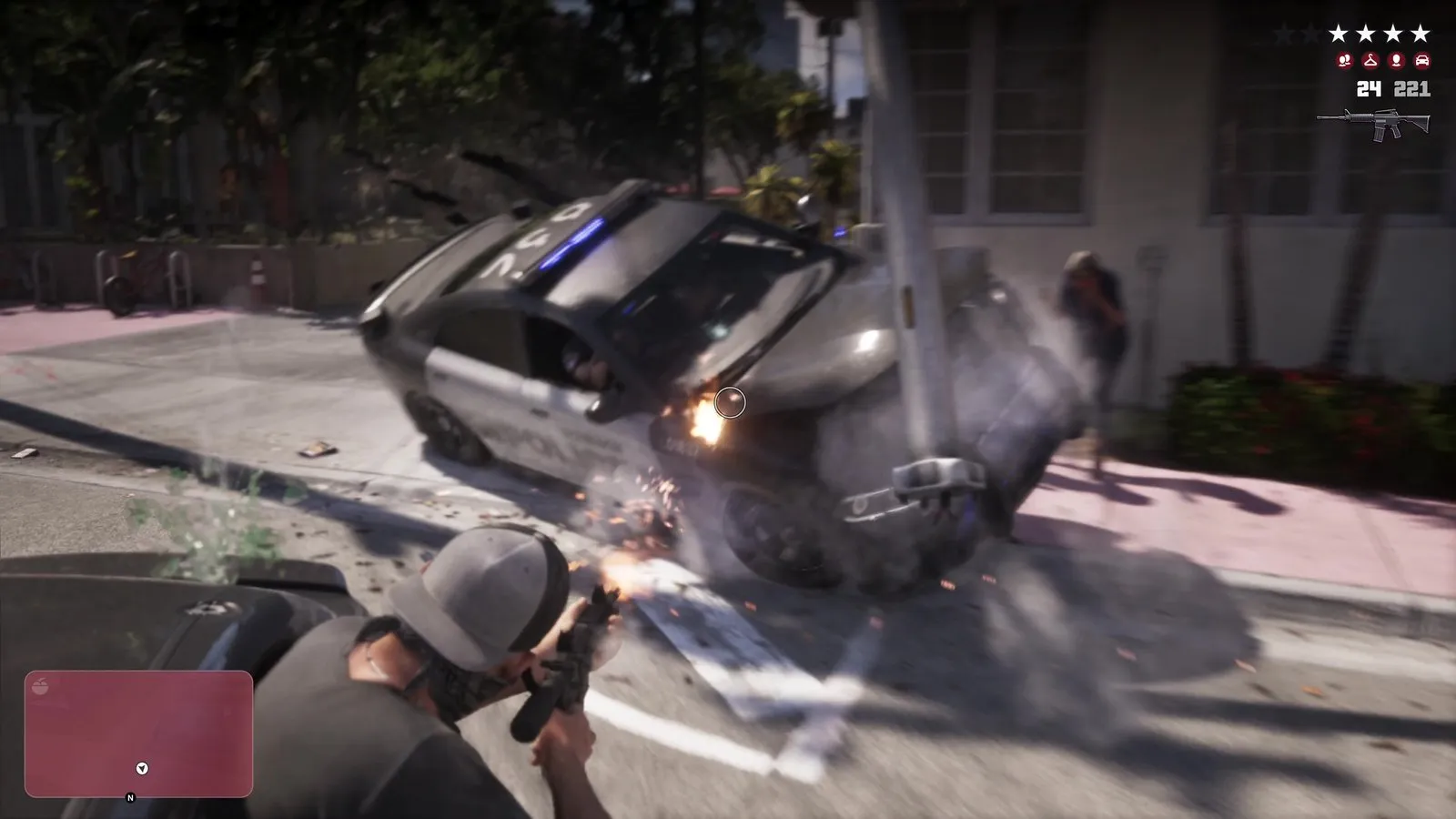 A masked man fires a rifle at a police sedan that tips onto its side after slamming into a utility pole.