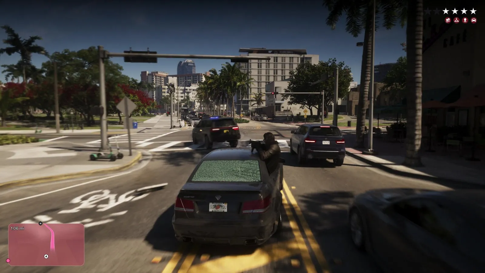 A passenger leans out of a dark sedan firing an automatic weapon as a dark SUV with blue lights crosses the intersection ahead.