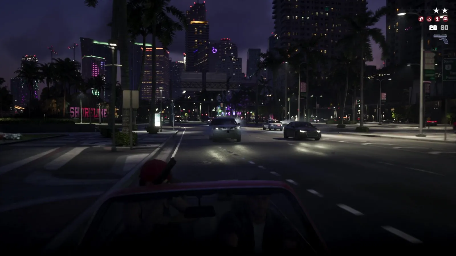 A police car with lights on chases a red convertible down a downtown boulevard at night.