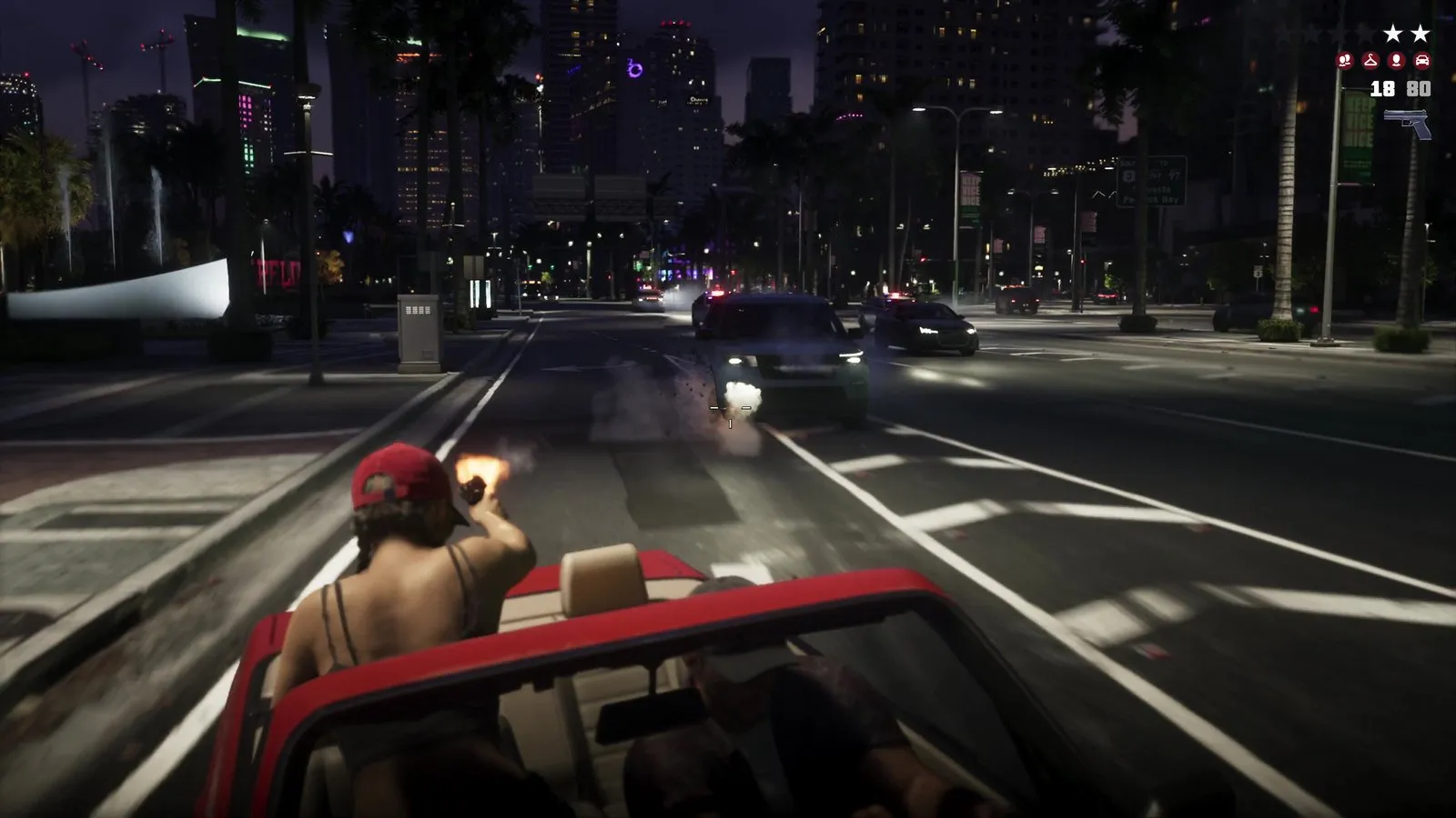A passenger in a red convertible fires a pistol at a light SUV leading several police cars on a downtown boulevard.