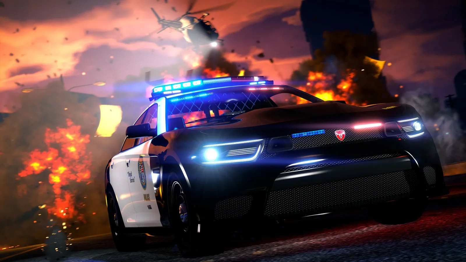 A black and white police sedan with its lights flashing races toward the camera as explosions and a helicopter fill the sky behind it.