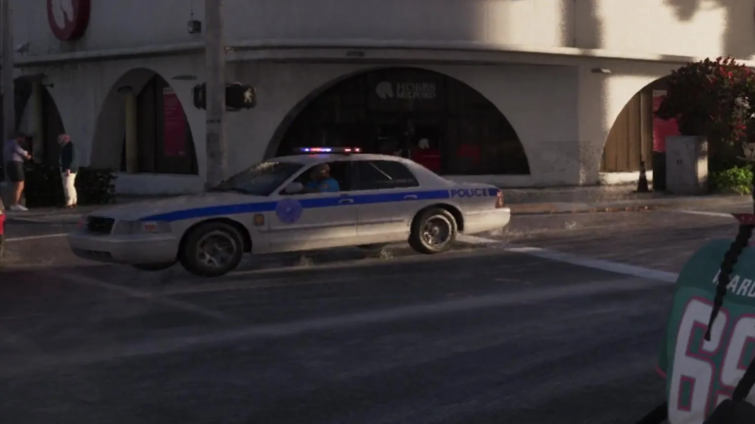 Close-up: white with a blue side stripe, a round blue and white door emblem and blue POLICE lettering on the rear door