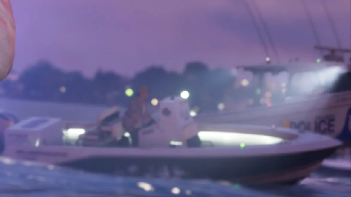 Close-up: white hull with dark POLICE lettering and a dark blue mark near the bow, tower with a searchlight